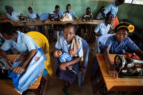 Jacqueline Furahas holds her four-month-old son in her arms in the middle of a classroom - Credit: Simon Townsley/The Telegraph