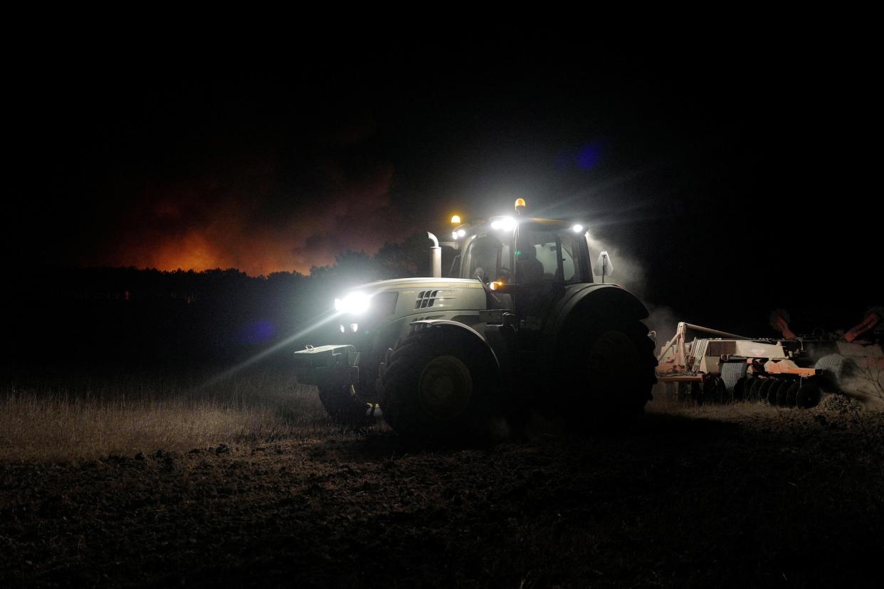 A tractor cleans up land during a wildfire in Aljezur, Portugal, 7 August (REUTERS)