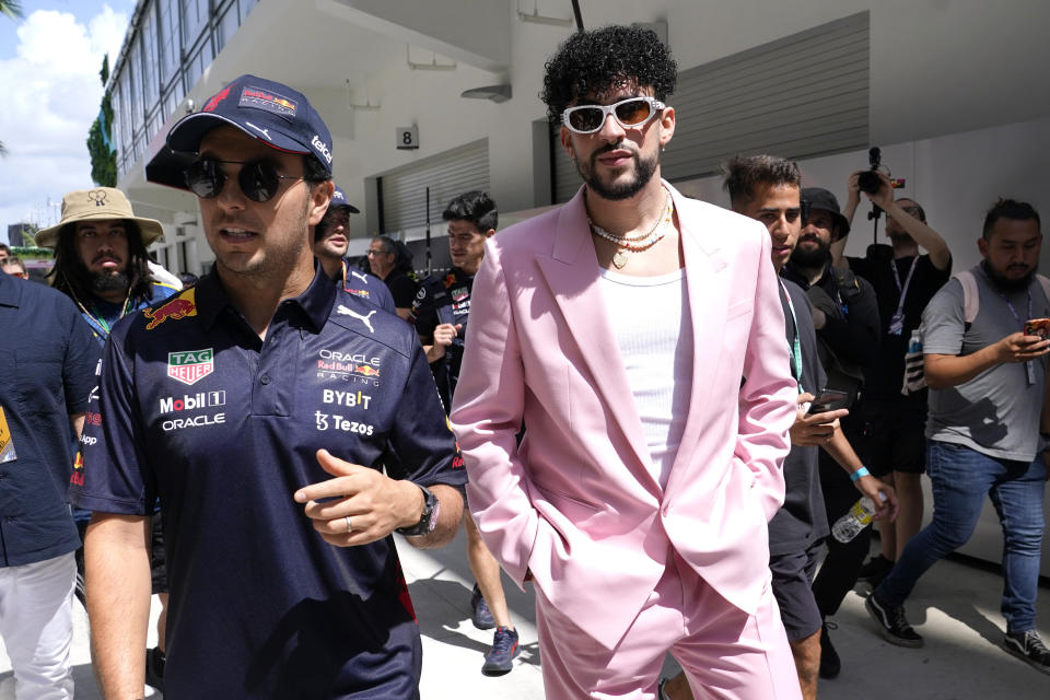 ARCHIVO - El piloto de Red Bull Sergio Pérez, de México, izquierda, camina con el reggaetonero puertorriqueño Bad Bunny antes del Gran Premio de Fórmula Uno de Miami en el Autódromo Internacional de Miami en Florida el 8 de mayo de 2022. A medida que el deporte crece en popularidad, las carreras también se están convirtiendo en una oportunidad para mini festivales de música. (Foto AP/Lynne Sladky, archivo)