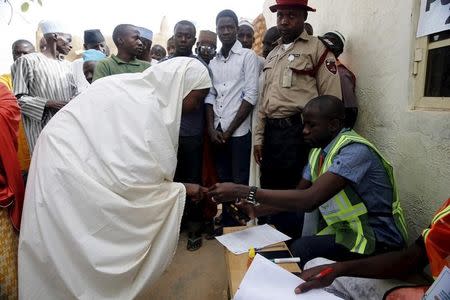An electoral officer scans the thumb print of a voter with a reader at a polling unit at the start of general elections in Daura, northwest Nigeria, March 28, 2015. REUTERS/Akintunde Akinleye