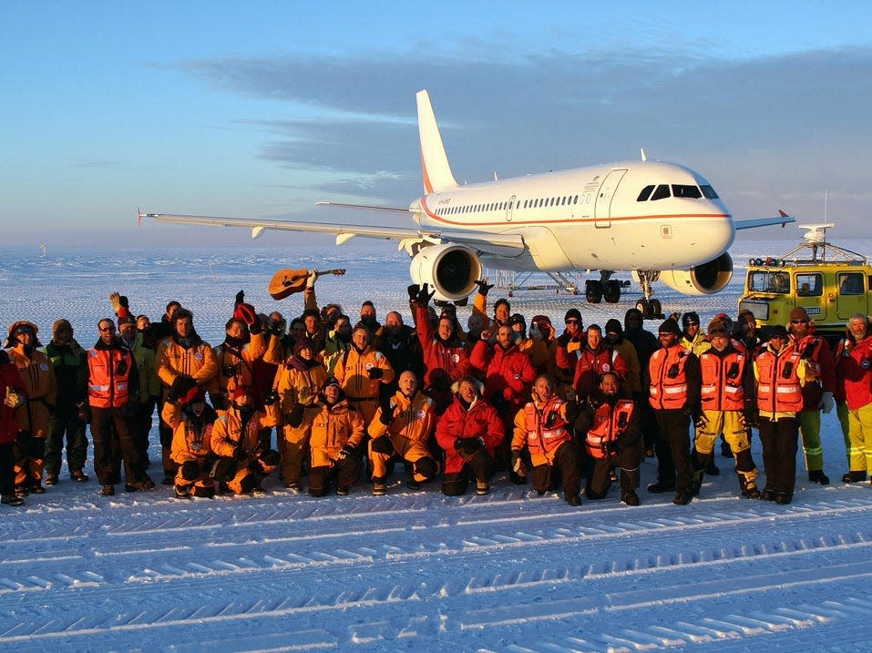 Passengers, scientists, government officials, and ground crew gather for a group photo on the purpose-built Wilkins glacial blue ice runway in front of the first Airbus A319 jet to carry passengers from Hobart, Australia, to Antarctica in 2008.