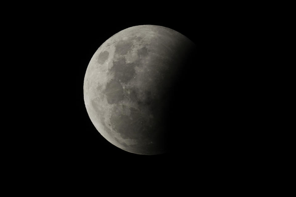 The Earth's shadow falls partly across the full moon at the start of a total lunar eclipse above Sydney Wednesday, May 26, 2021. The total lunar eclipse, also known as a super blood moon, is the first in two years with the reddish-orange color the result of all the sunrises and sunsets in Earth's atmosphere projected onto the surface of the eclipsed moon. (AP Photo/Mark Baker)