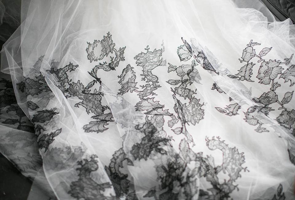 The cathedral-length light ivory tulle veil, detailed with hand-pieced black Chantilly lace.