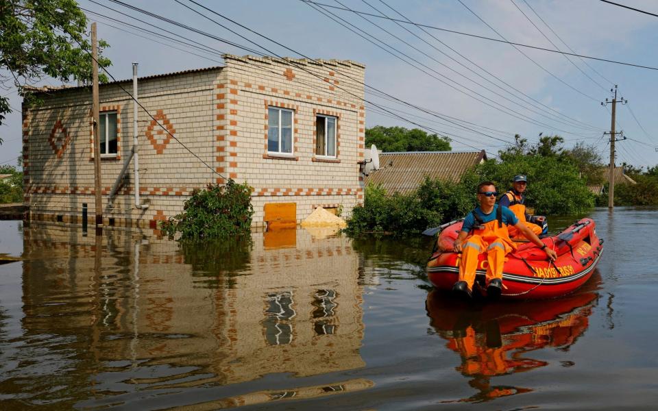 Members of Russia's emergencies ministry use an inflatable boat in a flooded area during a rescue operation - ALEXANDER ERMOCHENKO/REUTERS