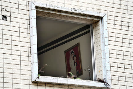 A wedding photograph, seen through a window, hangs on a wall in an apartment which was damaged in the 2008 Sichuan earthquake in the city of Beichuan, Sichuan province, China, April 6, 2018. REUTERS/Jason Lee