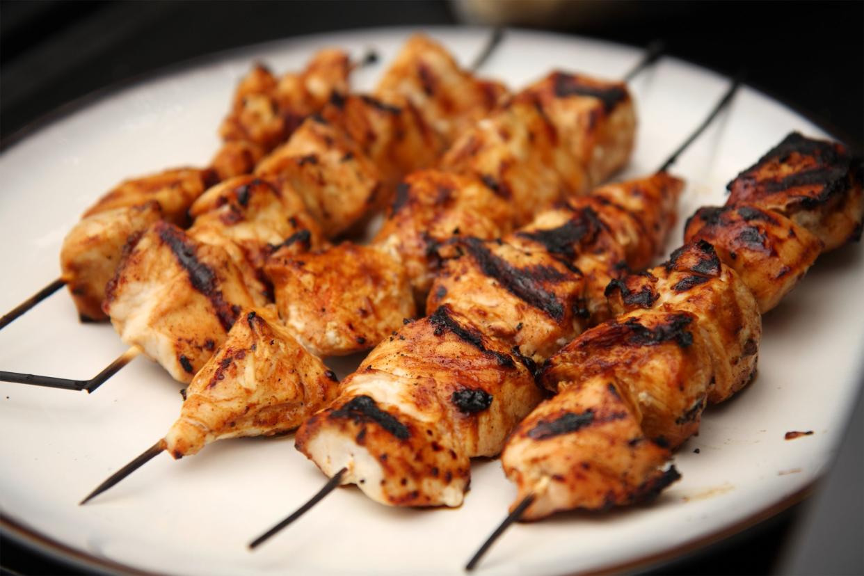 Five skewers of Middle Eastern-style grilled chicken kabobs on a white plate