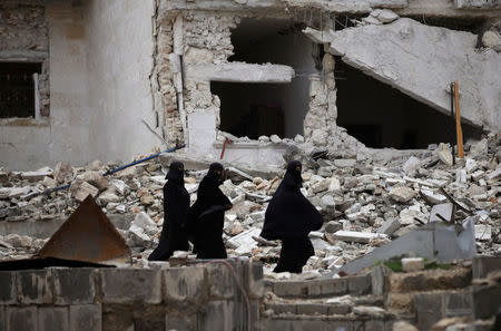 Women walk near damaged buildings in the northern Syrian city of al-Bab, Syria March 13, 2017. REUTERS/Khalil Ashawi