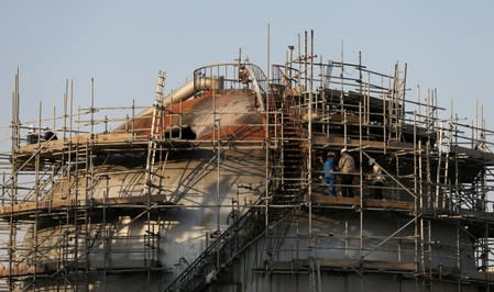 Workers are seen at the damaged site of Saudi Aramco oil facility in Abqaiq