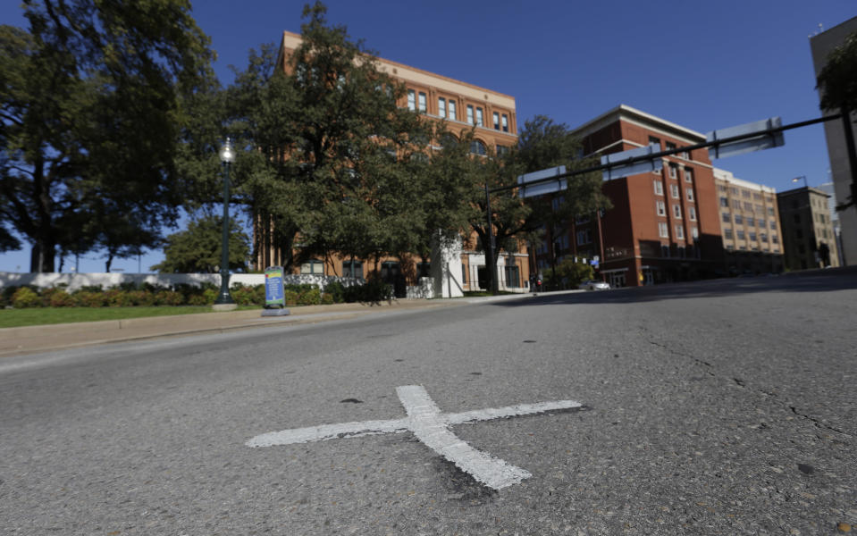 An X marks the spot on Elm Street on Tuesday, Nov. 12, 2013 where the first bullet hit President John F. Kennedy on Nov. 22, 1963 near the former Texas School Book Depository, now known as the Sixth Floor Museum, background, on Dealey Plaza in Dallas. (AP Photo/LM Otero)