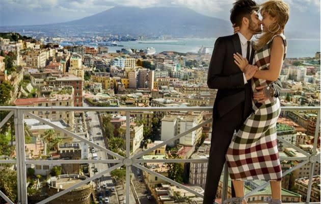 Gigi Hadid, wearing a Victoria Beckham dress, Jennifer Fisher earrings, and Miu Miu shoes, kisses Zayn, who sports a Saint Laurent suit and Jimmy Choo shoes. (Photo: Mario Testino for Vogue)