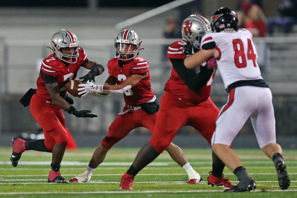 East running back Ziaire Stevens, left, takes a handoff from quarterback Darshaun Sales, right, during the first half of a Division III playoff game Friday in Akron.