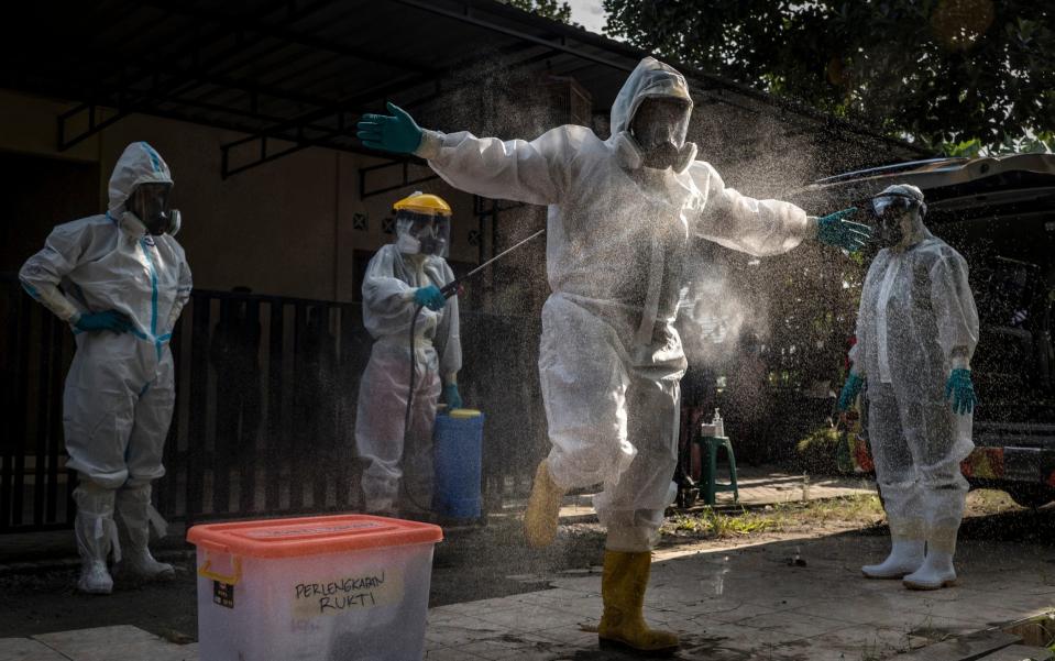 A volunteer undertaker is sprayed with disinfectant before recovering the body of a suspected Covid-19 victim in Yogyakarta, Indonesia on 22 July 2021 - Ulet Ifansasti/Getty Images