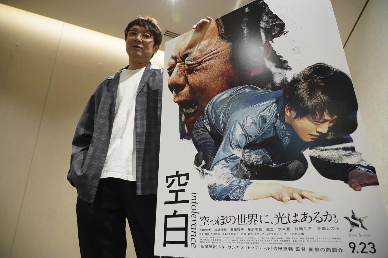 Keisuke Yoshida, Japanese film director and screenwriter, poses with a poster of his latest film "Intolerance (Kuhaku)" during an exclusive interview with The Associated Press Tuesday, Oct. 5, 2021, in Tokyo. Boxers, janitors, fishermen, the heroes of Yoshida’s movies are Japanese society’s angst-filled losers, struggling in an imperfect world. The director and his three latest works are featured at the Tokyo International Film Festival opening Oct. 30, 2021. (AP Photo/Eugene Hoshiko)