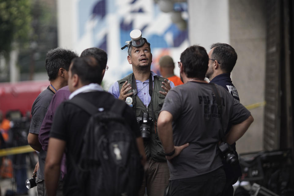 Investigators stand at the entrance of the Badim Hospital, where a fire left at least 11 people dead, in Rio de Janeiro, Brazil, Friday, Sept. 13, 2019. The fire raced through the hospital forcing staff to wheel patients into the streets on beds or in wheelchairs. (AP Photo/Leo Correa)