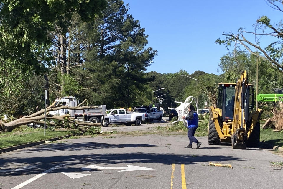 A man carries a piece of furniture through a neighborhood in Virginia Beach, Va. on Monday May 1, 2023. The City of Virginia Beach declared a state of emergency after a tornado moved through the area and damaged dozens of homes, downed trees and caused gas leaks. (AP Photo/Ben Finley)