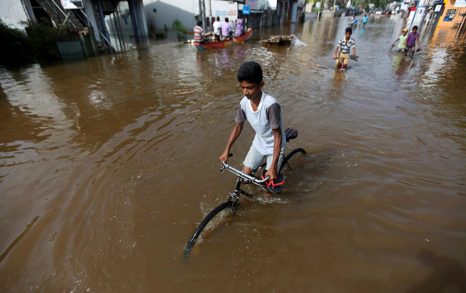 A boy rides his bike along a flooded road