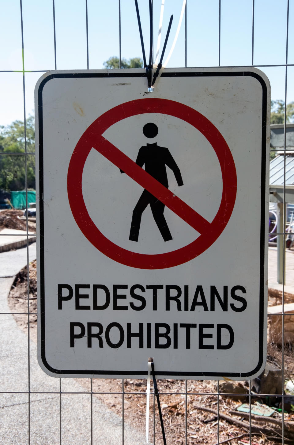 Pictured is a sign on a fence that says pedestrians prohibited.