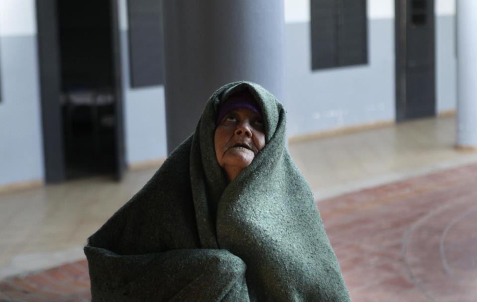 In this May 29, 2013 photo, a patient covers herself with a blanket in the courtyard of the Neuro-Psychiatric Hospital in Asuncion, Paraguay. Paraguay's only public psychiatric hospital is forced to feed hundreds of patients with donated food for lack of funding and there is no money for heating to protect patients from the biting chill during the winter months. (AP Photo/Jorge Saenz)