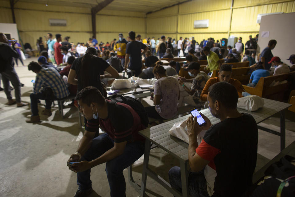 People wait at a warehouse run by the Mission: Border Hope nonprofit group, in Eagle Pass, Texas, May 23, 2022. The Border Patrol releases up to 1,000 migrants daily at Mission: Border Hope. The nonprofit group, run by the United Methodist Church, outgrew a church and moved to the warehouse in April amid the Biden administration's rapidly expanding practice of releasing migrants on parole, particularly those who are not subject to a pandemic rule that prevents migrants from seeking asylum.(AP Photo/Dario Lopez-Mills)