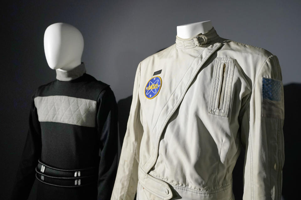 An ANSA flight suit costume prop, right, worn by actor Charlton Heston who played the character "George Taylor" on in the 1968 film, Planet of the Apes, sits on display by other items in a collection at Heritage Auctions, Thursday, Aug. 30, 2023, in Irving, Texas. While Greg Jein's work over nearly half a century making miniature models in Hollywood included such iconic creations as the alien mothership in "Close Encounters of the Third Kind," he was also a lifelong collector of costumes, props, scripts, artwork and photographs from the shows he loved, including countless rare items from the "Star Trek" and "Star Wars" franchises. Thousands of those items, including those Jein collected and those he created, will be offered up by Heritage Auctions next month in Dallas. (AP Photo/Tony Gutierrez)