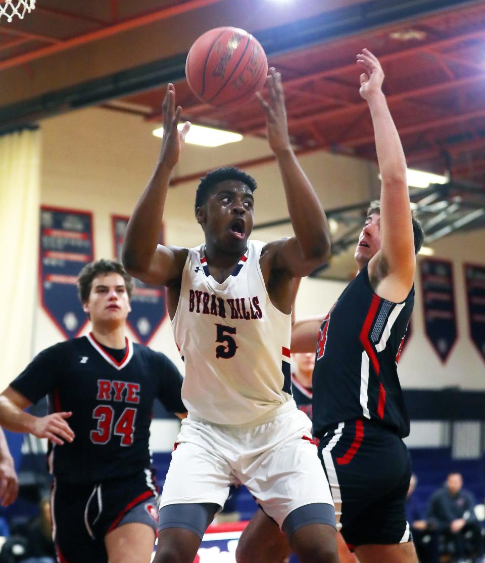 Byram Hills Zach Efobi (5) pulls down a rebound in front of Rye's Jake Kessner (24) during boys basketball action at Byram Hills High School in Armonk Jan. 26, 2024. Byram Hills won the game 66-53.