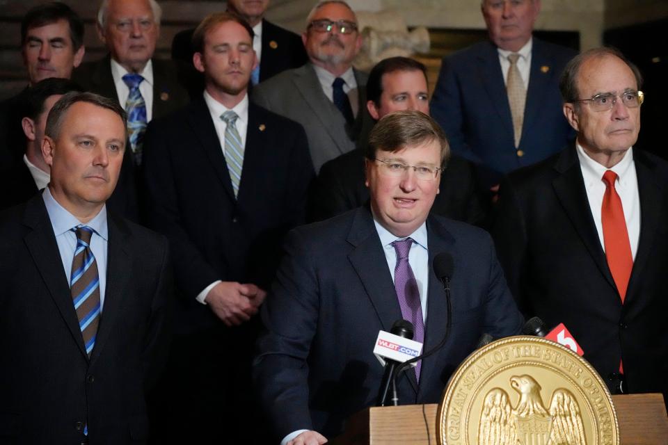 Mississippi Republican Gov. Tate Reeves, center, stands with House Speaker Jason White, R-West, left, and Republican Lt. Gov. Delbert Hosemann, right, as well as the legislators behind him, as he praises the passing of a state incentives package for a Mississippi factory that will manufacture batteries for electric vehicles — a project that promises 2,000 jobs, following a special session of the Mississippi Legislature, Thursday, Jan. 18, 2024, at the Mississippi Capitol in Jackson.