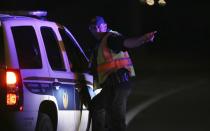 A Phoenix Police officer directs a patrol vehicle to the scene of a deadly shooting in Phoenix, Ariz., Sunday, March 29, 2020. At least three Phoenix police officers were shot Sunday night on the city's north side, authorities said. (AP Photo/Ross D. Franklin)