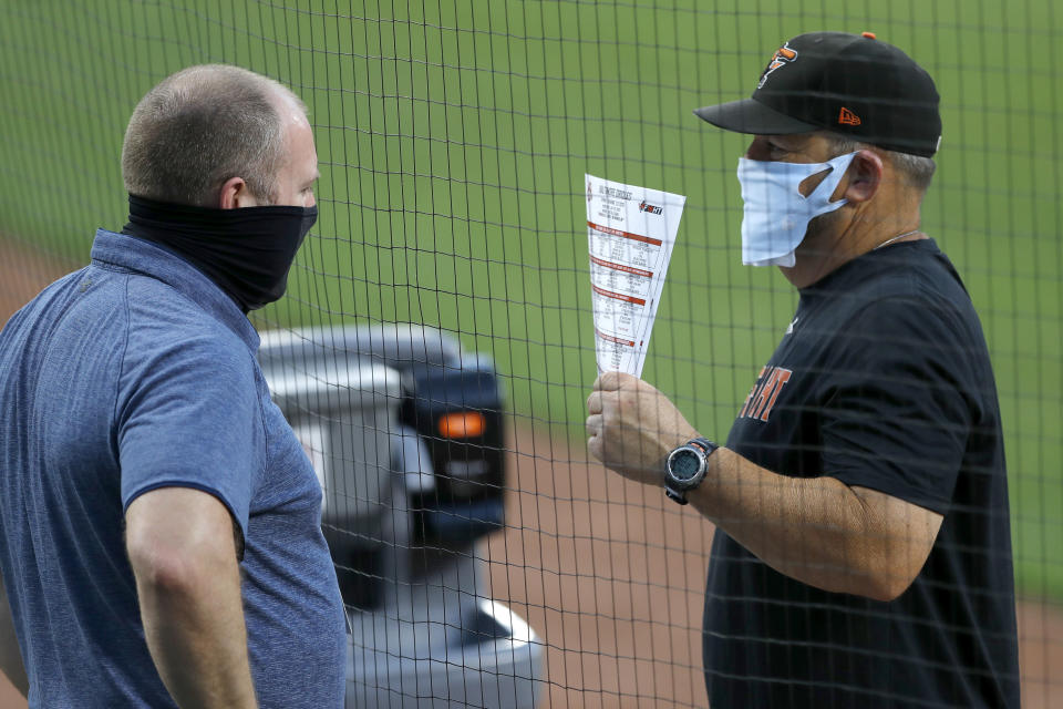 Baltimore Orioles director of baseball administration Kevin Buck, left, and field coordinator Tim Cossins wear masks to protect against COVID-19 as they talk during an intrasquad game at baseball training camp Tuesday, July 14, 2020, in Baltimore. (AP Photo/Julio Cortez)