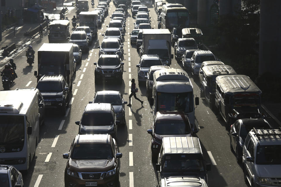 A woman crosses a highway as traffic builds up near a checkpoint during a stricter lockdown as a precaution against the spread of the coronavirus on the outskirts of Marikina City, Philippines on Friday, August 6, 2021. Thousands of people jammed coronavirus vaccination centers in the Philippine capital, defying social distancing restrictions, after false news spread that unvaccinated residents would be deprived of cash aid or barred from leaving home during a two-week lockdown that started Friday. (AP Photo/Basilio Sepe)