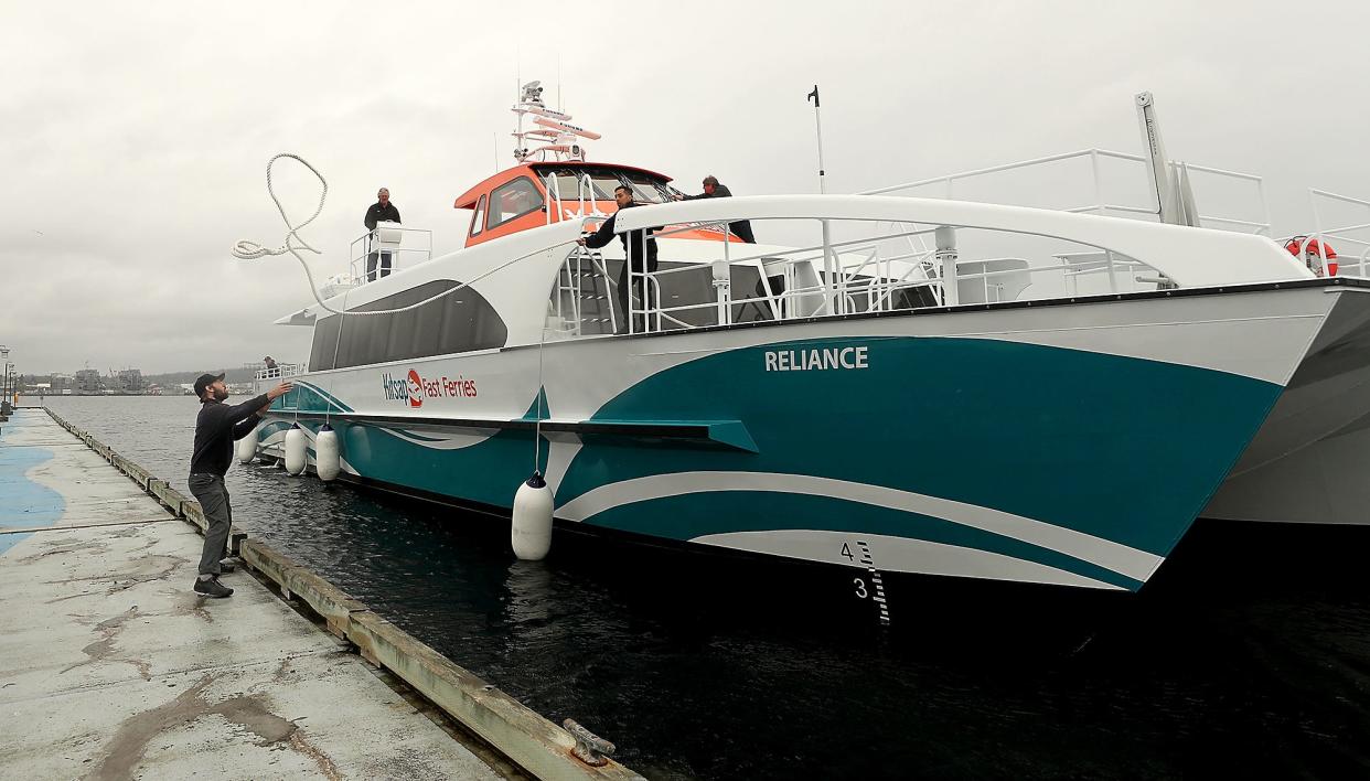 FILE — Marine engineer Nick Taylor, left, gets ready to catch the lines tossed by senior deck hand Lou Trevino, center, as Kitsap Transit's fast ferry the Reliance docks in Port Orchard in April 2019.