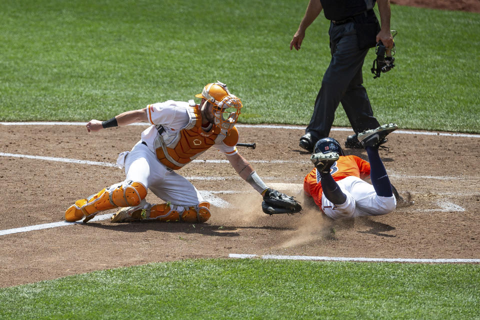 Virginia infielder Alex Tappen, front right, slides to home for a run against Tennessee catcher Connor Pavolony, left, in the seventh inning during a baseball game in the College World Series, Sunday, June 20, 2021, at TD Ameritrade Park in Omaha, Neb. (AP Photo/John Peterson)