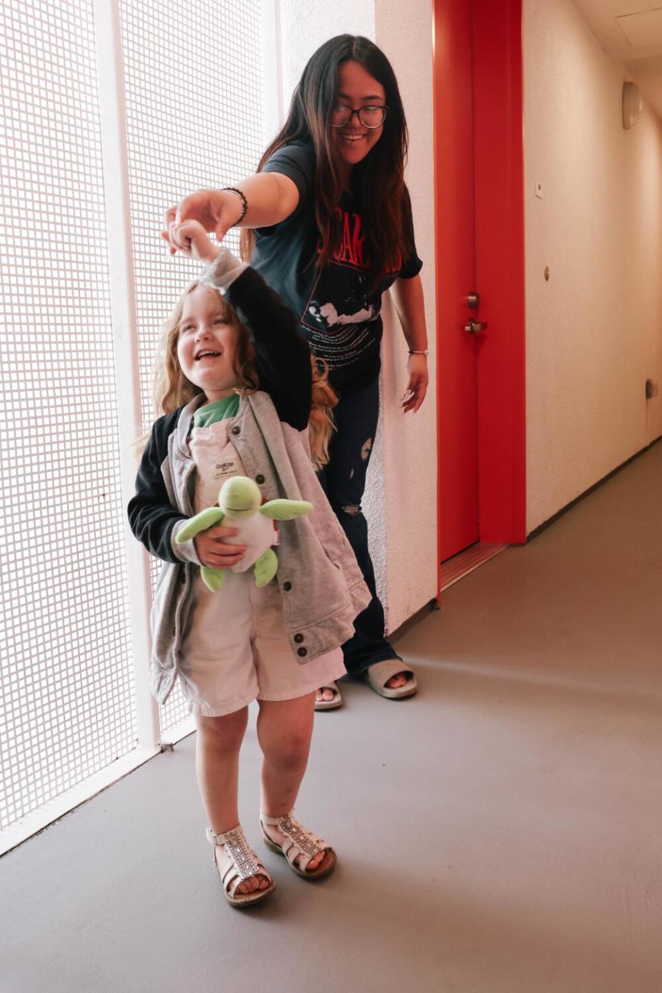 A mother holding her daughter's hand while she twirls around.