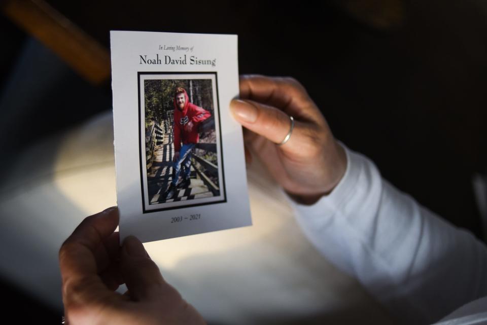 Trina Coolman holds the funeral memorial card from her late son Noah Sisung's funeral, Monday, Feb. 21, 2022, at their home in Holt. The 18-year-old was shot and killed last October in Lansing.