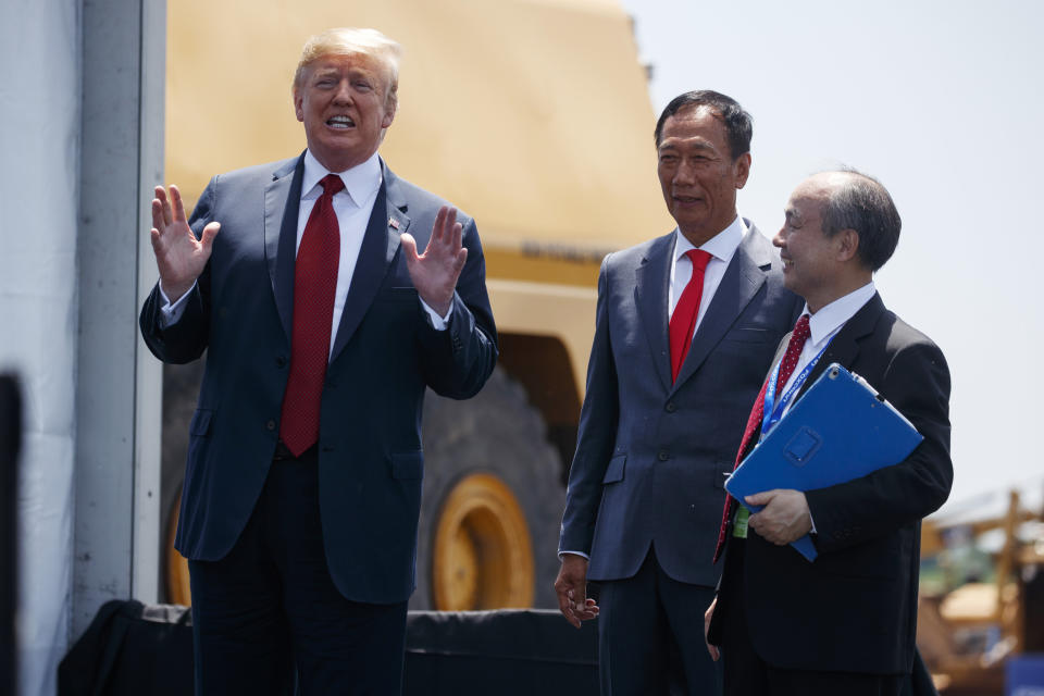 President Donald Trump talks to reporters while standing with Foxconn chairman Terry Gou, center, and CEO of SoftBank, Masayoshi Son, during a groundbreaking event, Thursday, June 28, 2018, in Mt. Pleasant, Wis. (AP Photo/Evan Vucci)