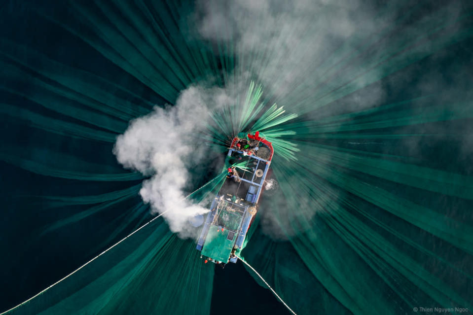 Una fotograf&#xed;a a&#xe9;rea de humo saliendo de un bote, con redes verdes en el agua.