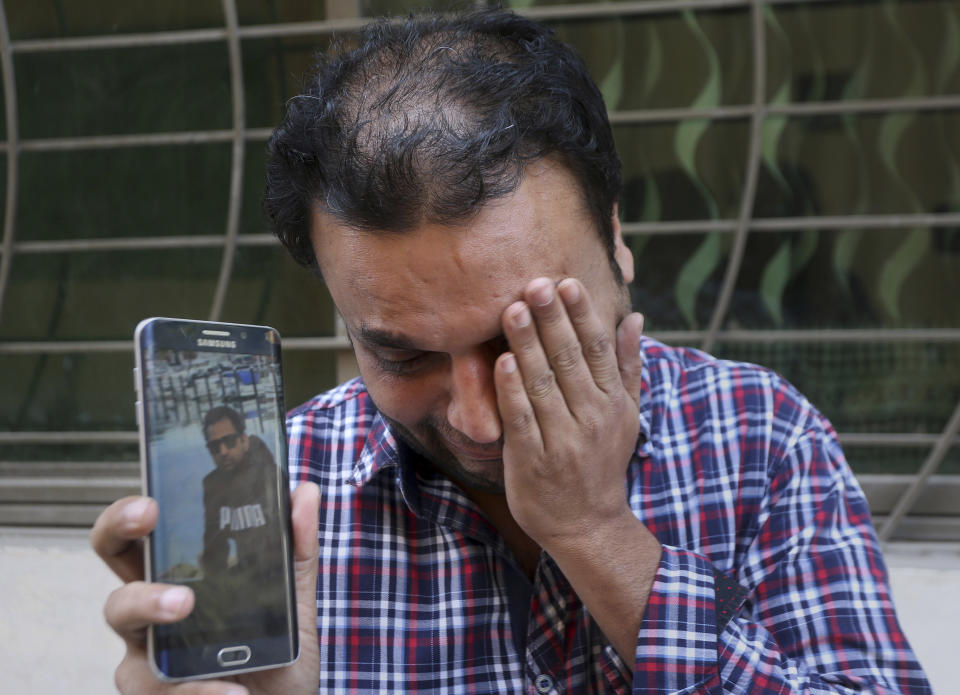 A relative weeps while showing the picture of Sohail Shahid, a Pakistani citizen who was killed in Christchurch mosque shootings, on his cell phone outside his home in Lahore, Pakistan, Sunday, March 17, 2019. Pakistan's foreign ministry spokesman says three more Pakistanis have been identified among the dead increasing the number of Pakistanis to nine killed in the mass shootings at two mosques in the New Zealand city of Christchurch. (AP Photo/K.M. Chaudary)