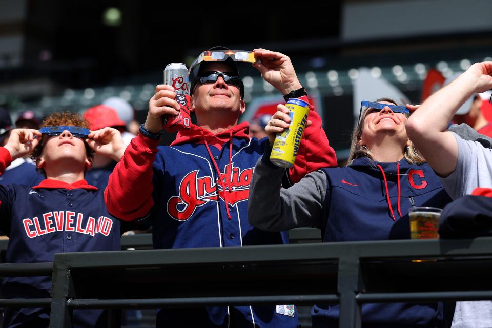 Cleveland Guardians fans look up at the solar eclipse before the home opener against the Chicago White Sox at Progressive Field on April 8, 2024 in Cleveland, Ohio.