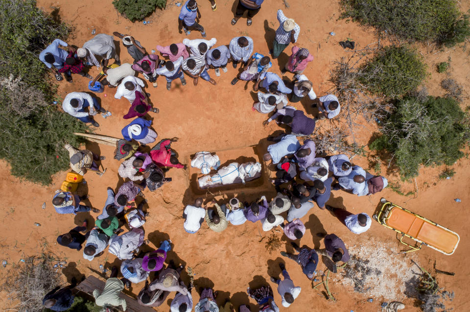 In this photo taken Thursday, April 30, 2020, medical workers in protective suits, accompanied by mourners, bury the body of an elderly man believed to have died of the coronavirus in Mogadishu, Somalia. Years of conflict, instability and poverty have left Somalia ill-equipped to handle a health crisis like the coronavirus pandemic. (AP Photo)