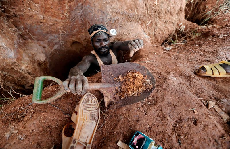 FILE PHOTO: An informal gold miner carries a shovel as he climbs out from inside a gold mining pit at the site of Nsuaem-Top