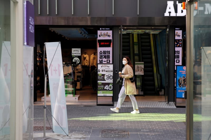 Woman wearing mask to prevent getting coronavirus, following outbreak of COVID-19, walks in a shopping district in Seoul