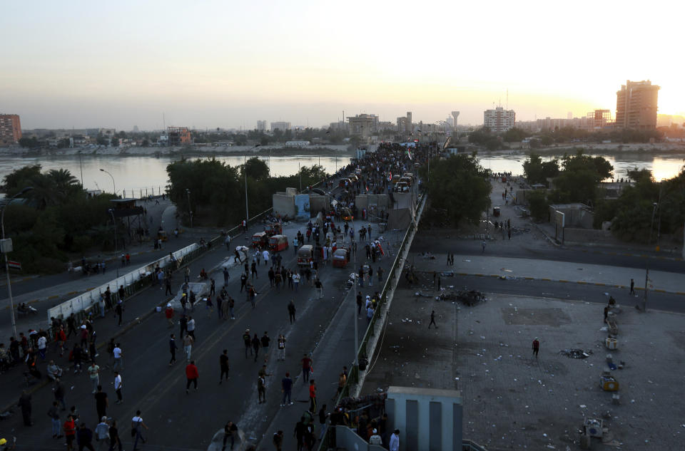 Protesters take control of some concrete walls and barriers erected by security forces to close the Sinak bridge leading to the Green Zone government areas, during clashes between Iraqi security forces and anti-government demonstrators in Baghdad, Iraq, Saturday, Nov. 16, 2019. (AP Photo/Hadi Mizban)