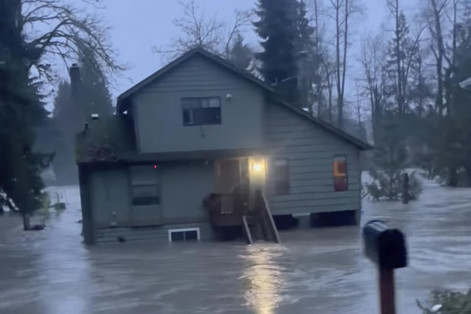 In this image from video provided by Kira Mascorella, a house is inundated by flood waters in Granite Falls, Wash., Tuesday, Dec. 5, 2023. An atmospheric river has brought heavy rain, flooding and warm winter temperatures to the Pacific Northwest, closing rail links, schools and roads as it shattered daily rainfall and temperature records in Washington state. (Kira Mascorella via AP)