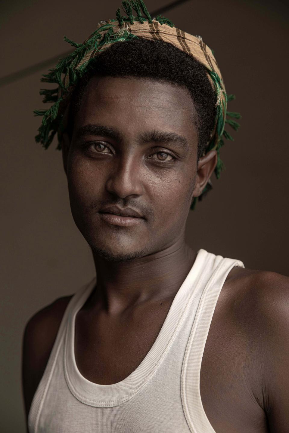 In this July 21, 2019 photo, 20-year-old Hussein Asfar, a migrant from Ethiopia who was a victim of physical abuse when he landed in Yemen, poses for a portrait in the "22nd May Soccer Stadium," destroyed by war in Aden, Yemen. Over the summer, the stadium became a temporary refuge for thousands of migrants. At first, security forces used it to house migrants they captured in raids. Other migrants showed up voluntarily, hoping for shelter. The IOM distributed food at the stadium and arranged voluntary repatriation back home for some. The soccer pitch and stands became a field of tents, with clothes lines strung up around them. (AP Photo/Nariman El-Mofty)