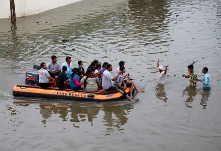 Fire officials evacuate people from a flooded neighbourhood after heavy rains in Ahmedabad. REUTERS/Amit Dave