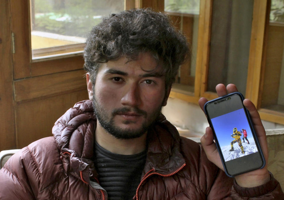 Pakistani climber Shehroz Kashif, 19, shows a picture on his cell phone of him holding a Pakistani flag on the summit of K2, during an interview with The Associated Press, in Skardu, a town in the Gilgit Baltistan region of northern Pakistan, Sunday, Aug. 1, 2021. The young mountaineer who last week scaled the second-highest mountain on earth, said Sunday he felt a “sense of achievement” as he stood atop the K2 summit and hoisted the Pakistani flag. (AP Photo/M.H. Balti)