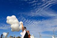 <p>Michelle Trigo, who now lives in San Antonio but grew up in the Sutherland Springs area, carries balloons to lay near the site of Sunday’s shooting at the First Baptist Church of Sutherland Springs, Texas, Monday, Nov. 6, 2017. (Photo: Mark Mulligan/Houston Chronicle via AP) </p>