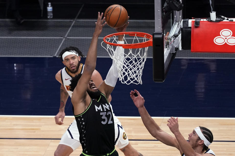 Minnesota Timberwolves' Karl-Anthony Towns (32) reaches for a rebound as Denver Nuggets' JaVale McGee, left, and Aaron Gordon watch during the first half of an NBA basketball game Thursday, May 13, 2021, in Minneapolis. (AP Photo/Jim Mone)