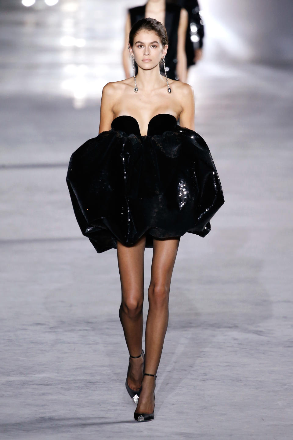 <p>The 16-year-old made a splash at Yves Saint Laurent in a plunging black mini and dramatic drop earrings.</p>