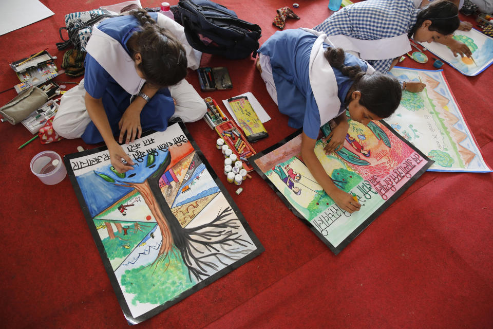 Indian school children create art work related to environment awareness in Prayagraj, India , Friday, Aug. 9, 2019. More than a million Indians planted saplings as part of a government campaign to tackle climate change and improve environment in the country’s most populated state. (AP Photo/Rajesh Kumar Singh)