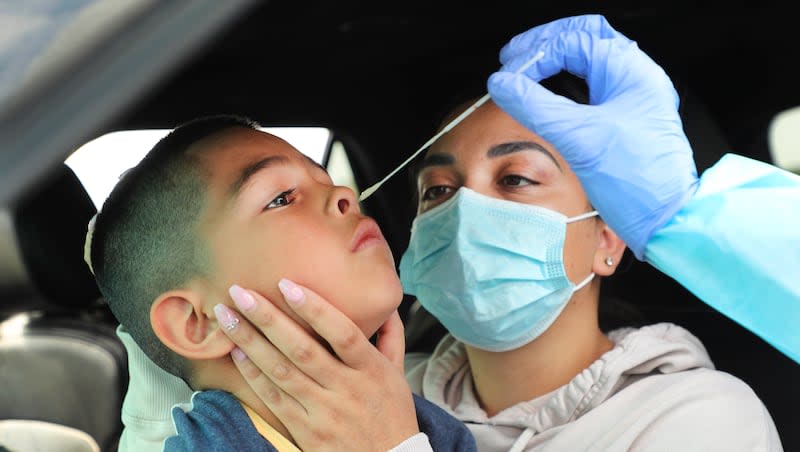 Yanet Alcaraz holds her son Nathan, 7, as he is tested for COVID-19 by the Salt Lake County Health Department in the parking lot of the Maverik Center in West Valley City on Sunday, Aug. 23, 2020.